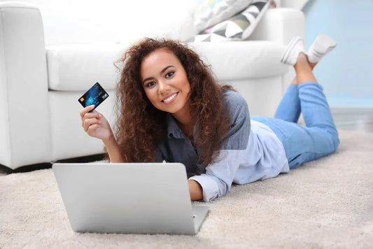 Smiling woman shopping online with a laptop and credit card, representing digital buyers on Etsy and Shopify